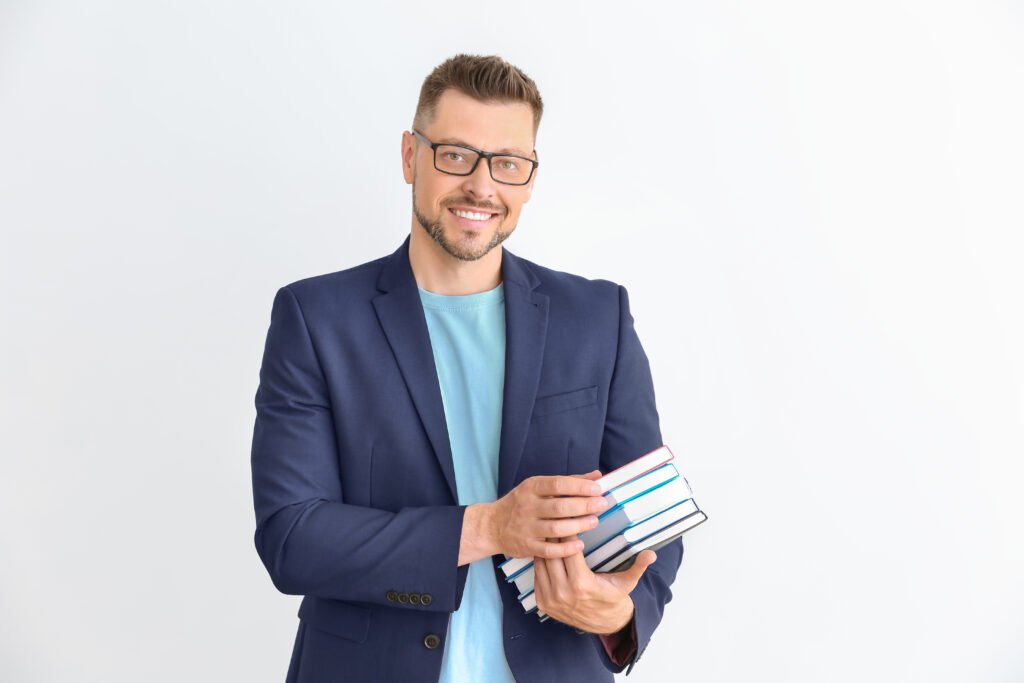 handsome male teacher with books on light background handsome male teacher with books on light background